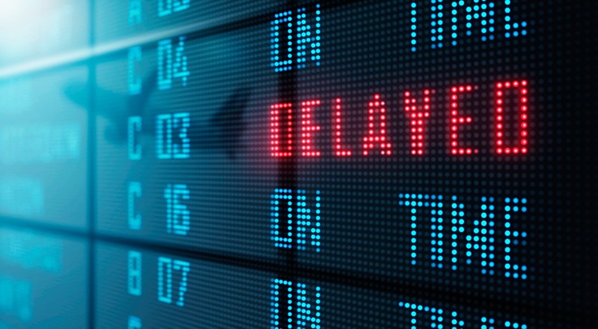 Anzeigetafel, auf der eine Zeile in Rot „Delayed“ meldet, während die übrigen „On Time“ zeigen