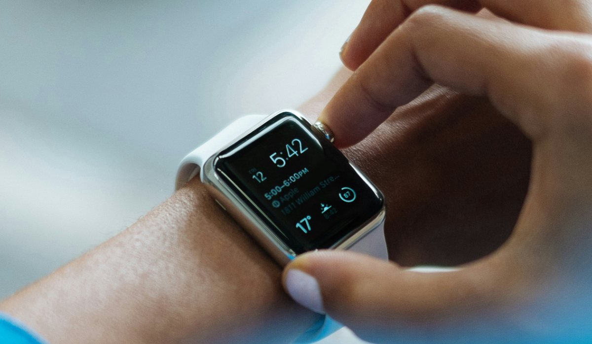 Hand am Handgelenk tippt auf eine Smartwatch, die Uhrzeit und einen Termin anzeigt